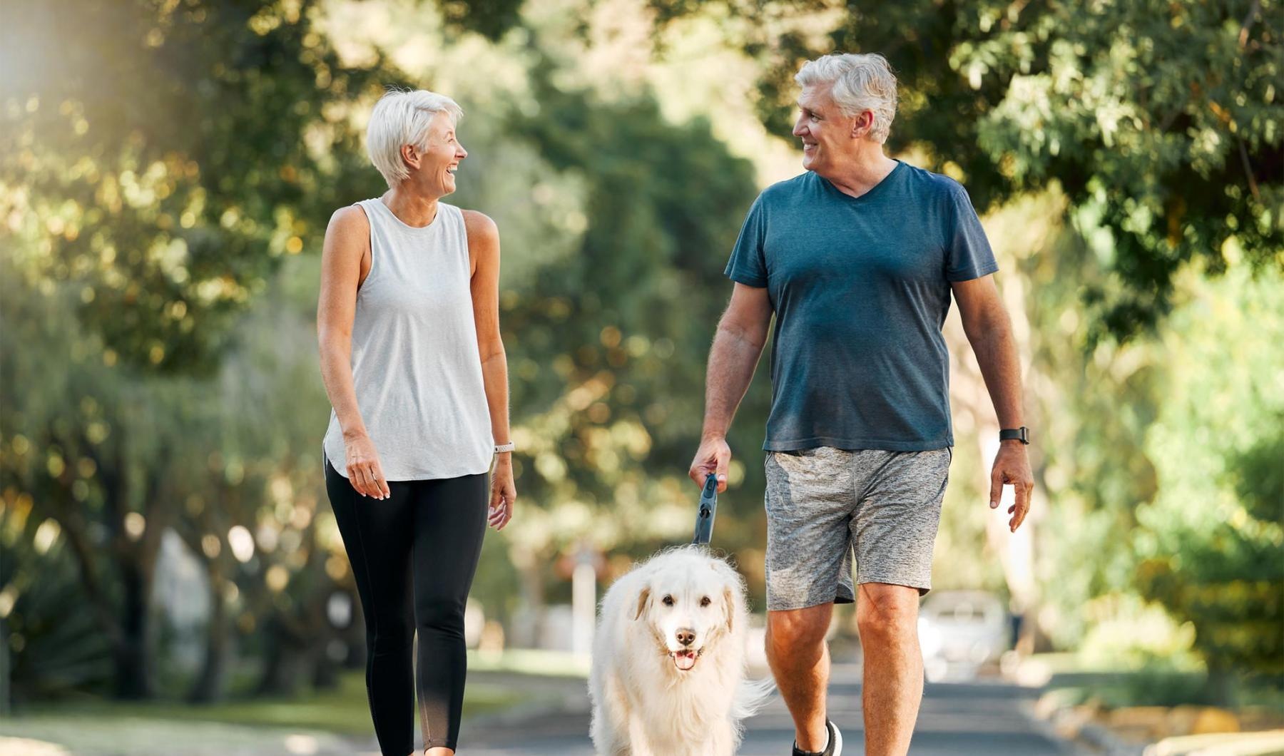King's Reserve Sanford is a pet-friendly community! a man and a woman walking a dog on a leash